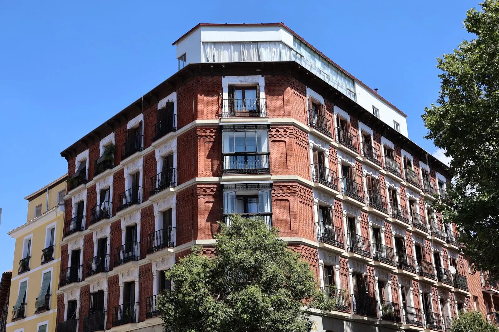 Edificio de viviendas de ladrillo rojo con balcones en Madrid