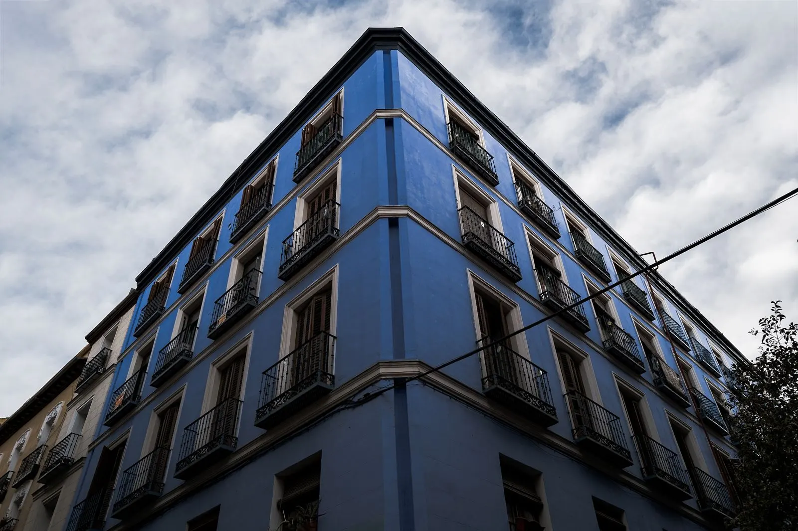 Fachada azul de un edificio de viviendas en Madrid vista desde abajo