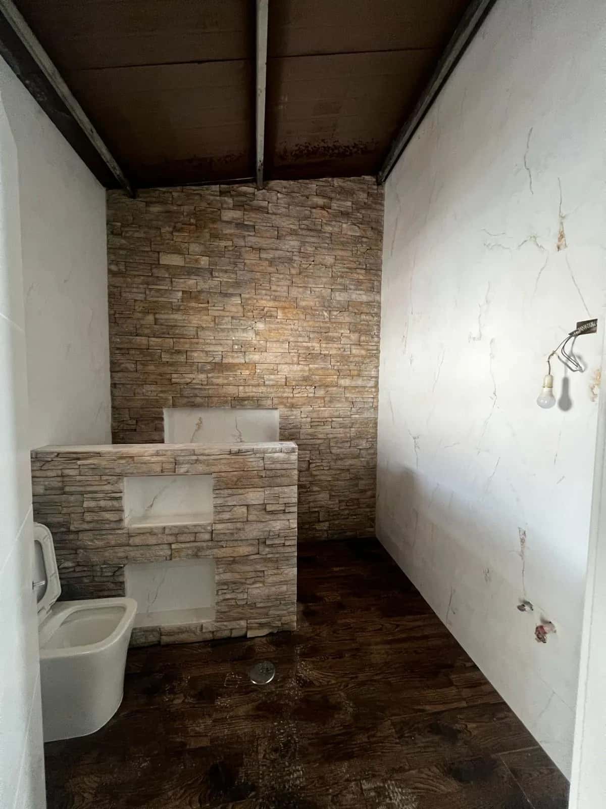 Baño en reforma con tomas de agua preparadas y murete revestido de piedra