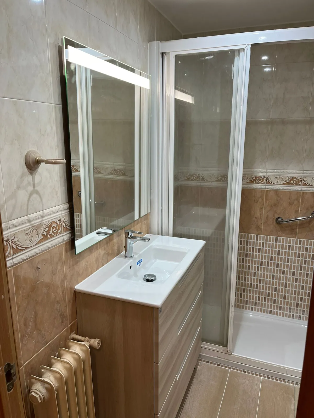 Baño reformado con mueble de lavabo, espejo con luz y mampara de ducha