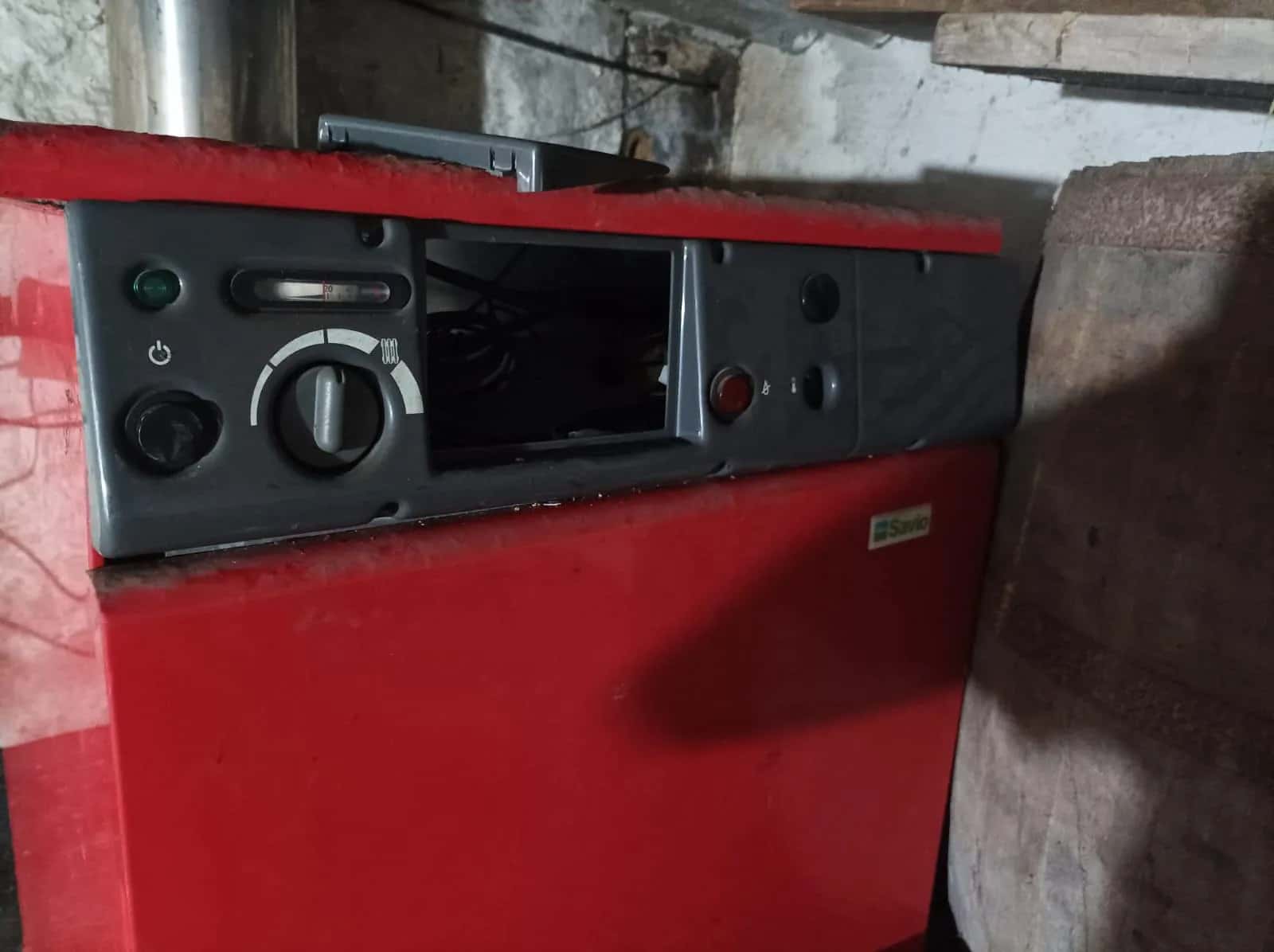 Caldera de pie roja con el panel de mandos desmontado para su revisión