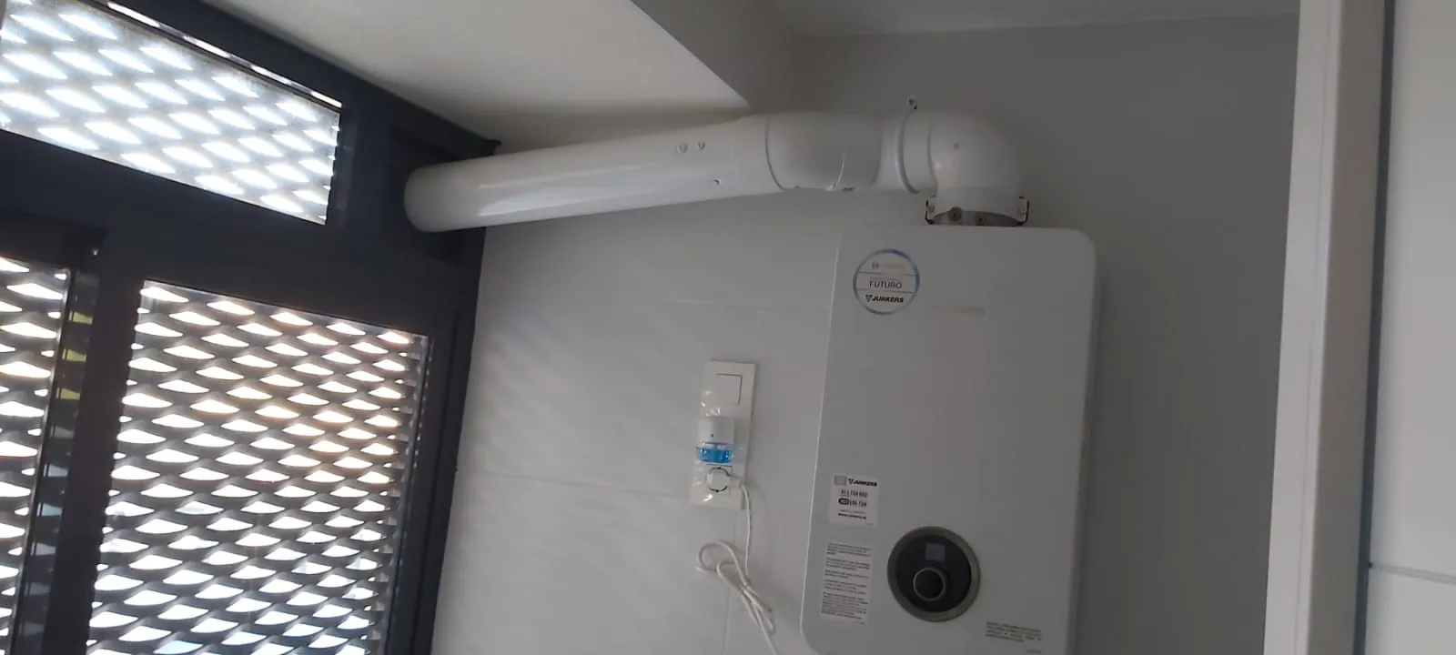 Calentador de gas con salida de humos instalado en la pared de una galería