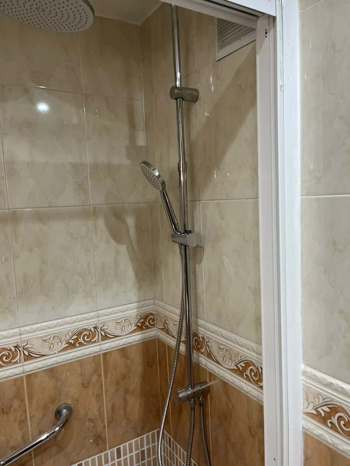 Columna de ducha con rociador y barra de apoyo sobre un plato de ducha nuevo