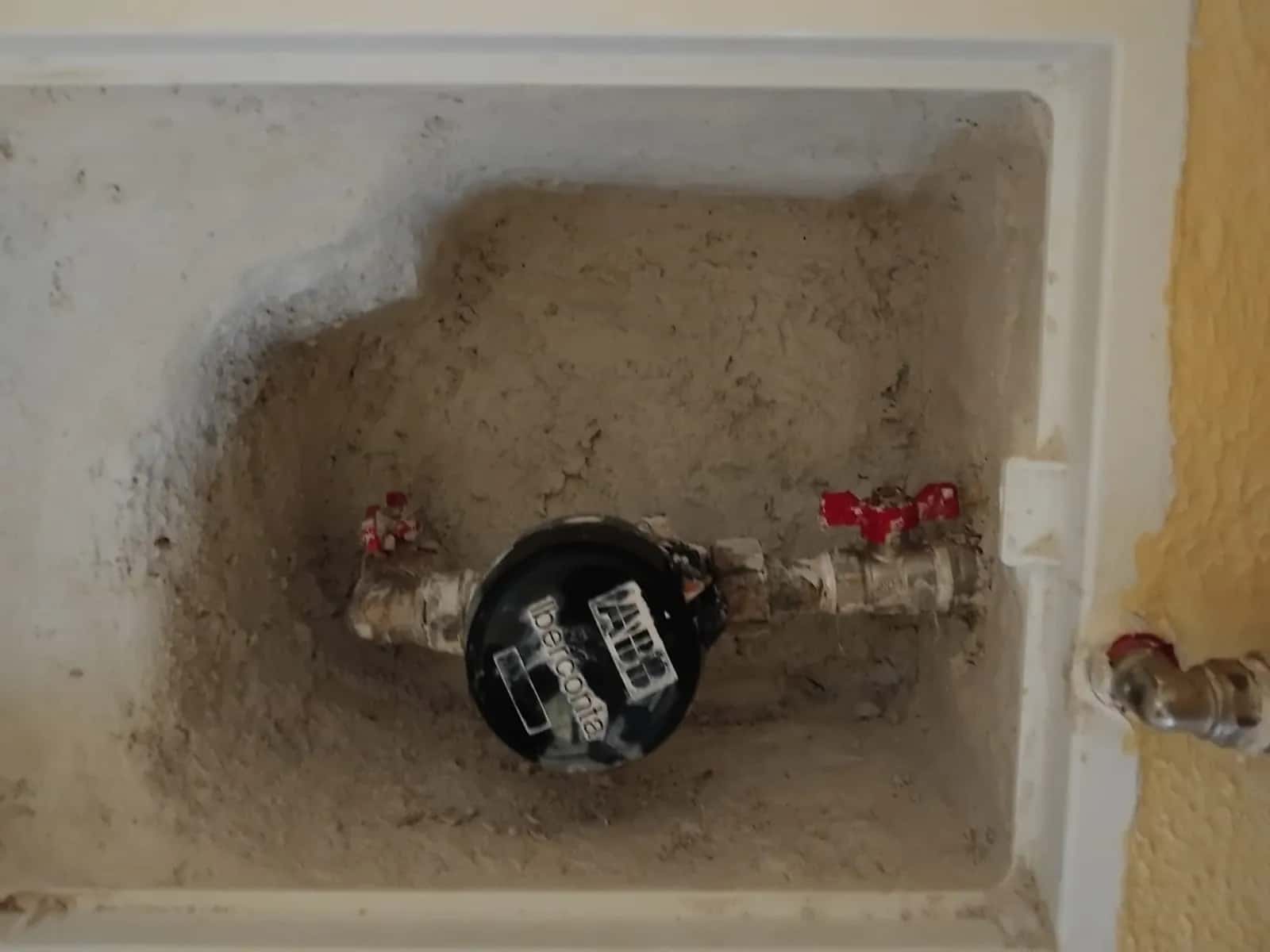 Contador de agua con dos llaves de paso dentro de una hornacina en la pared
