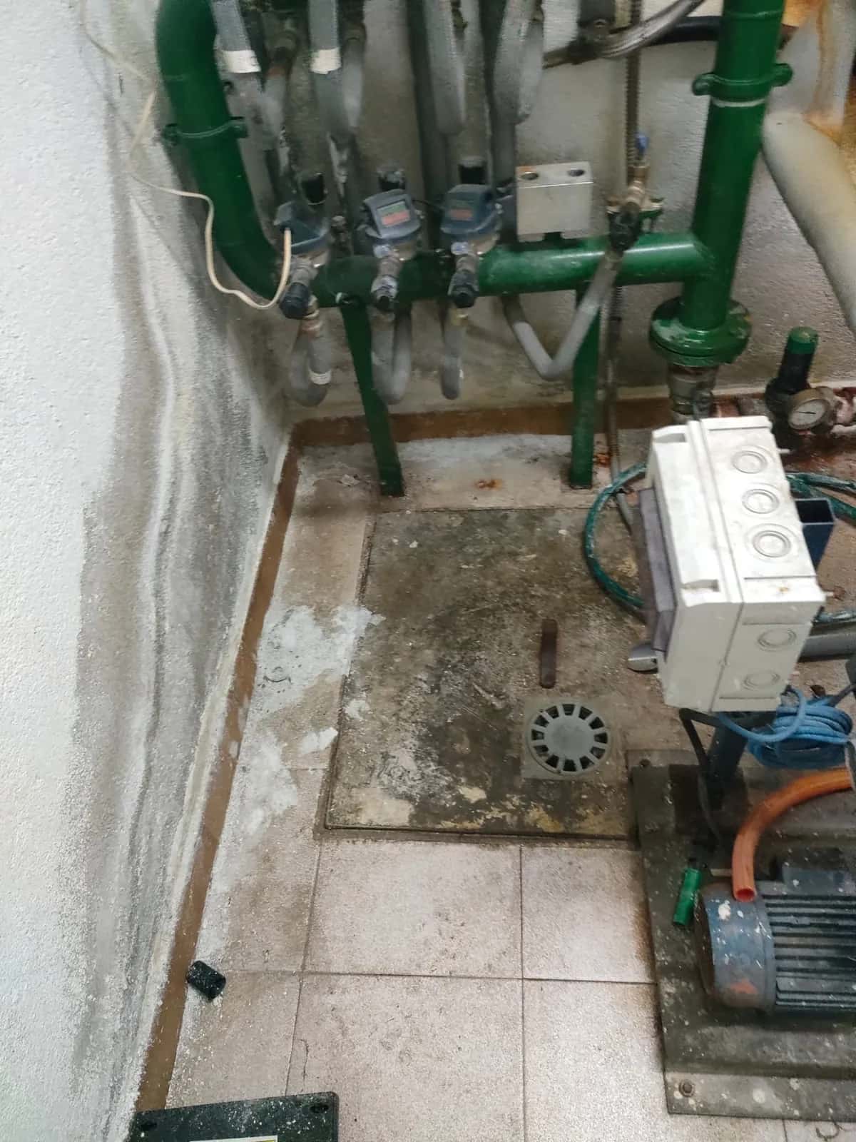 Cuarto de contadores con batería de contadores, montantes verdes y grupo de presión