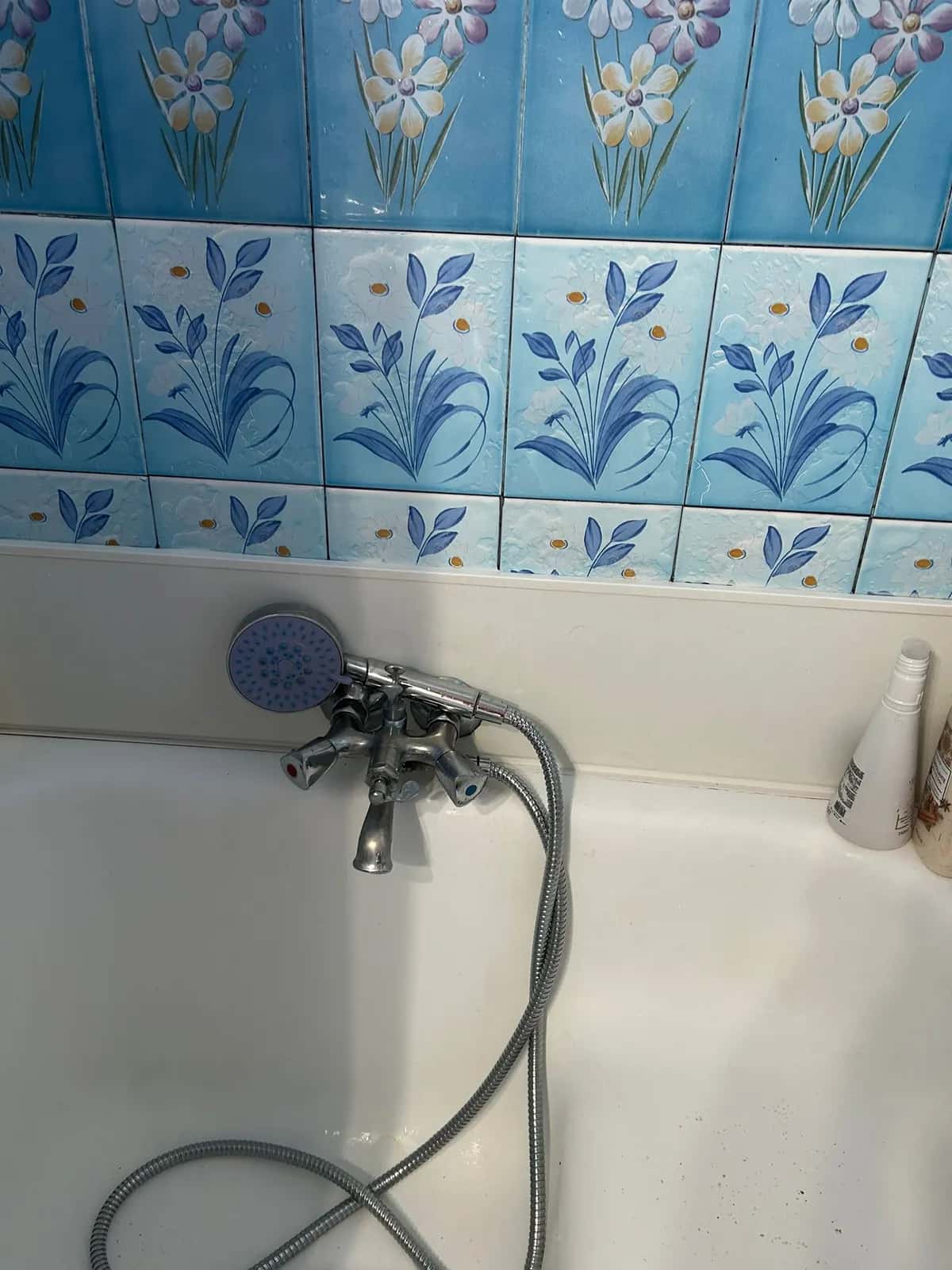 Grifo de bañera antiguo con ducha de teléfono en un baño de azulejo