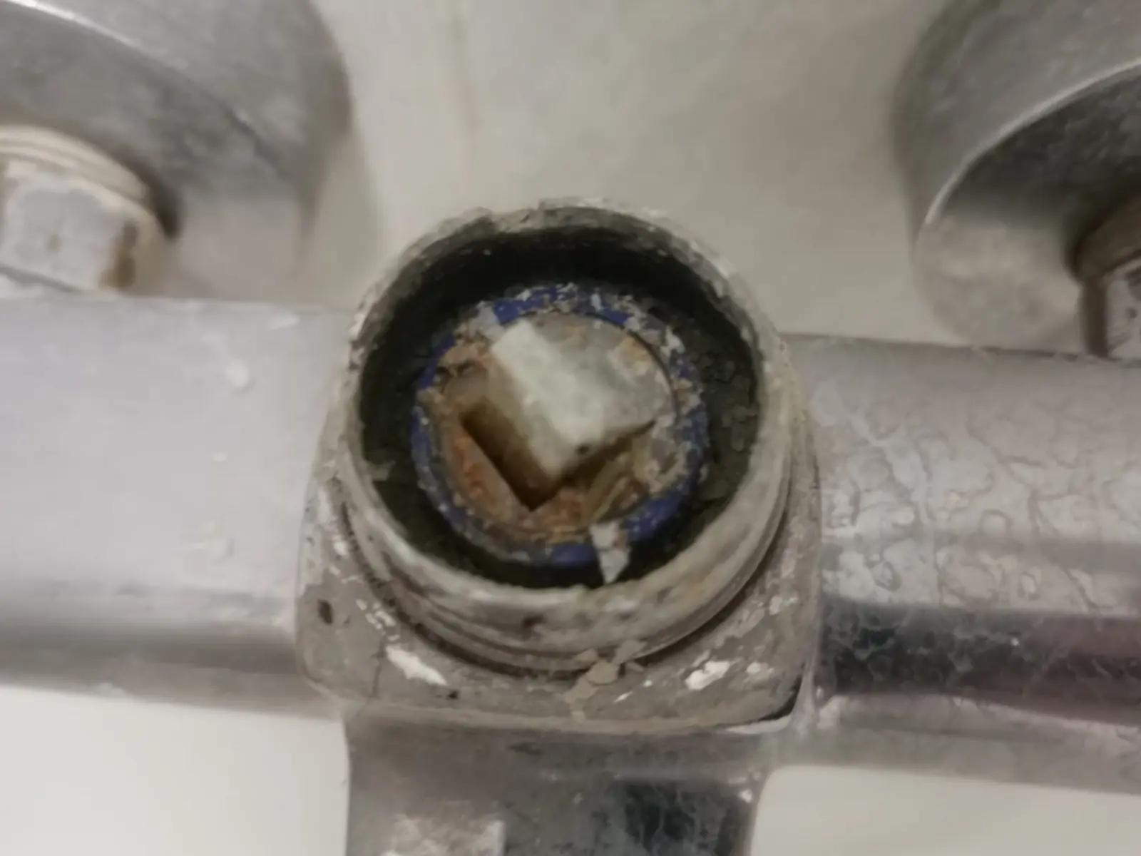 Grifo de bañera sin maneta con el cartucho interior a la vista y cal acumulada