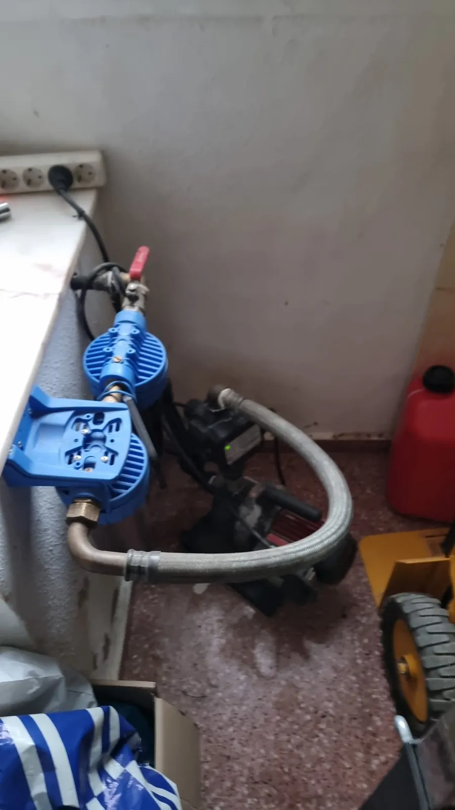 Grupo de presión doméstico con bomba, filtros y manguera flexible en un trastero