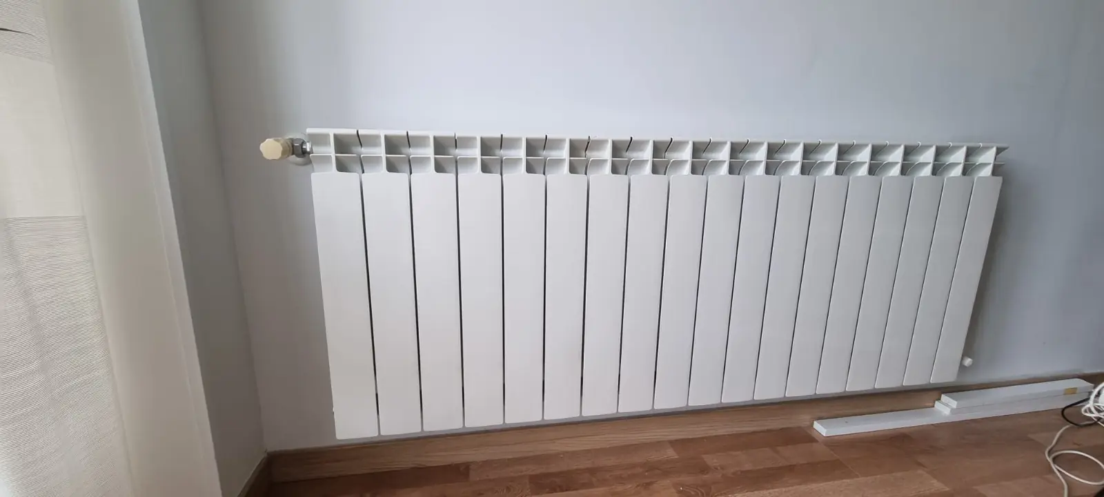 Radiador de aluminio blanco de muchos elementos sobre un suelo de madera