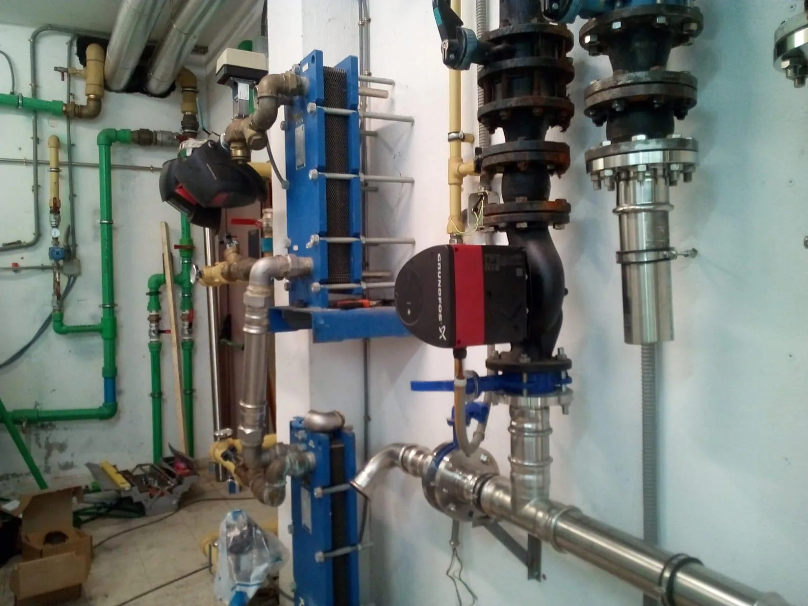 Sala de calderas con intercambiador de placas, bomba circuladora y tuberías de acero inoxidable