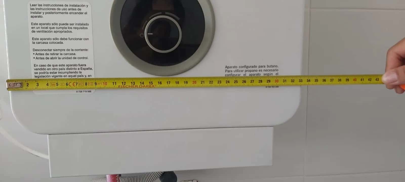 Técnico midiendo con cinta métrica el ancho de un calentador de gas