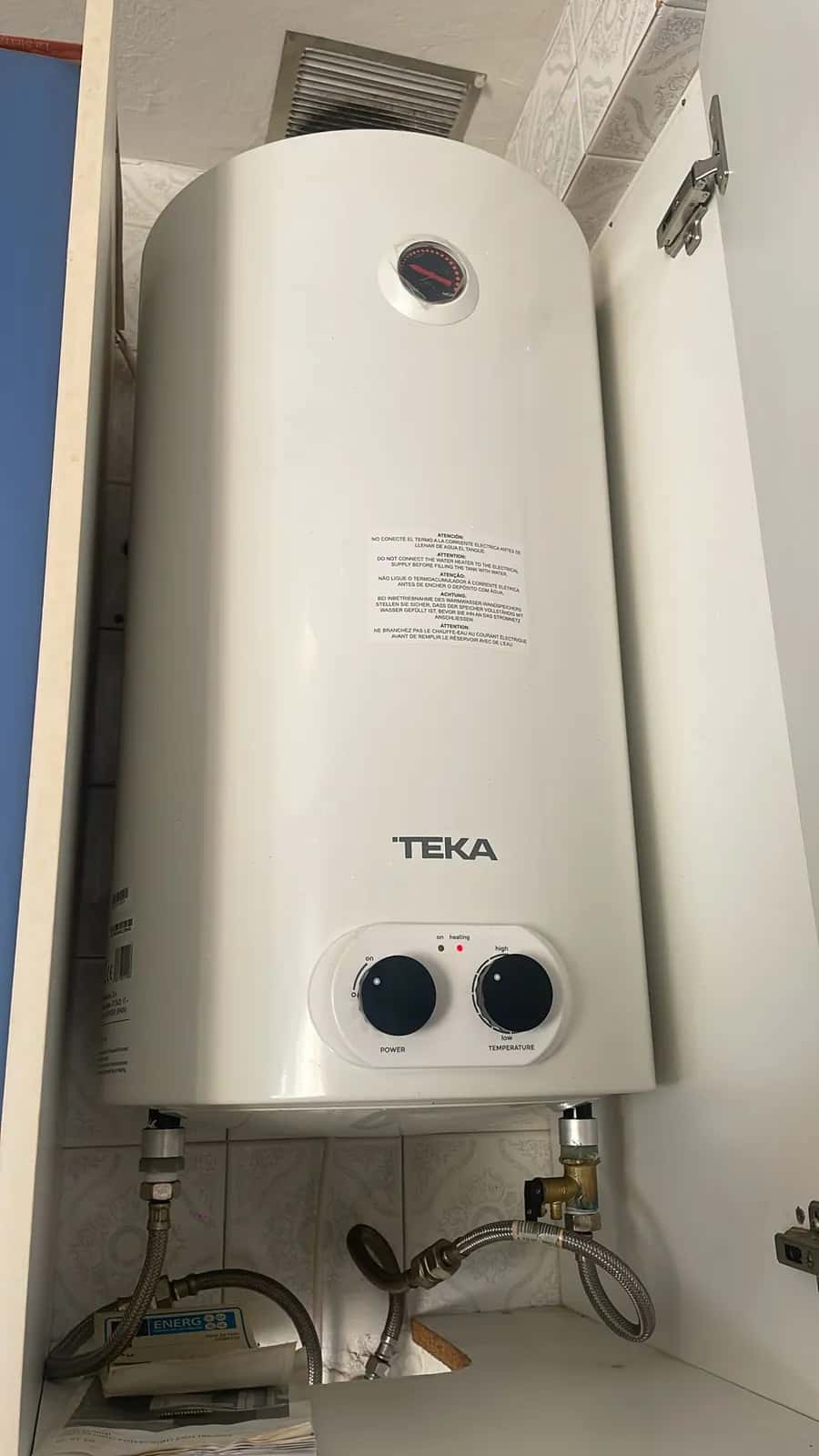 Termo eléctrico vertical instalado dentro de un armario con sus latiguillos y válvula