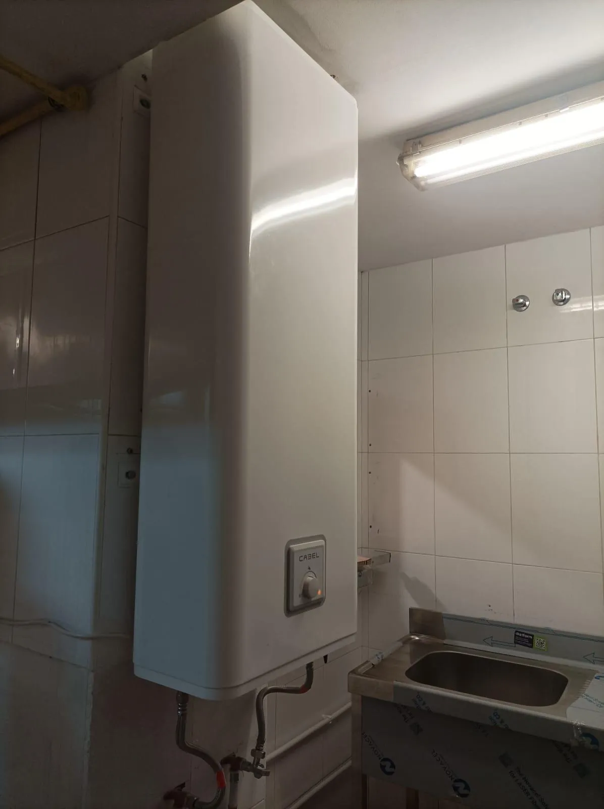 Termo eléctrico vertical instalado sobre un fregadero de acero inoxidable