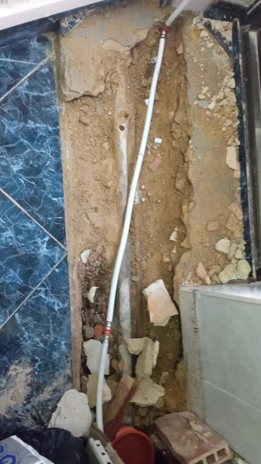 Zanja abierta en el suelo con nueva tubería multicapa blanca junto a la antigua